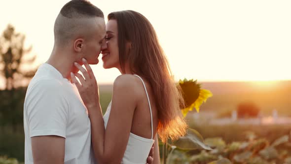 Happy Young Attractive Couple in Sunflower Field Together at Sunset in Slow Motion