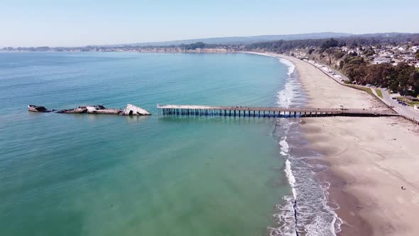 Sunken concrete freighter SS Palo Alto and wooden pier, aerial flying forward view. Sandy California