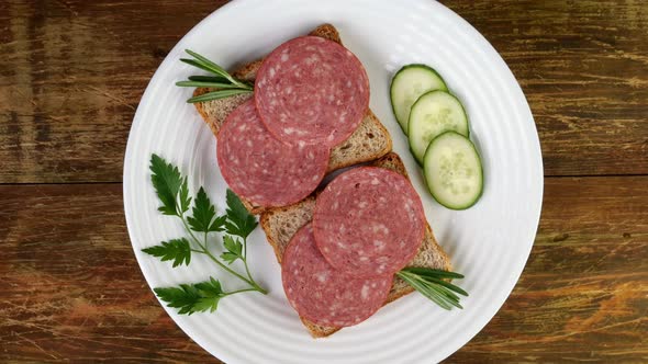 Open Salami Sandwiches with Bread Cucumber Parsley on White Plate Rotate Slowly