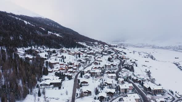 Aerial view of mountain town and valley covered by snow in winter - Houses an