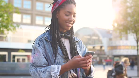 Black young woman typing on smart phone in Berlin