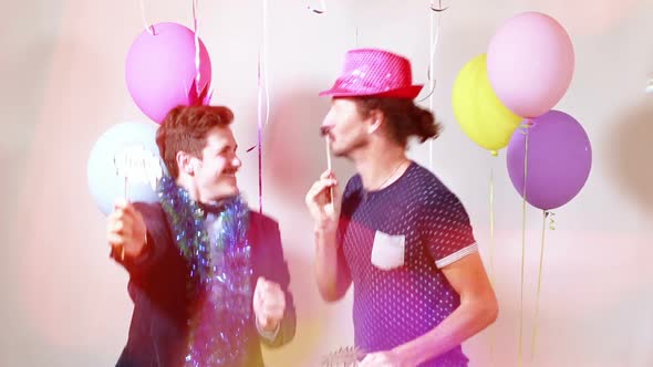 Two happy men dancing with props in photo booth