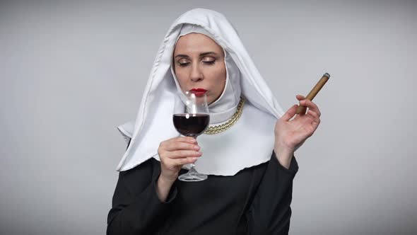 Bored Caucasian Woman in Nun Costume Smoking Cigar Drinking Red Wine Looking at Camera