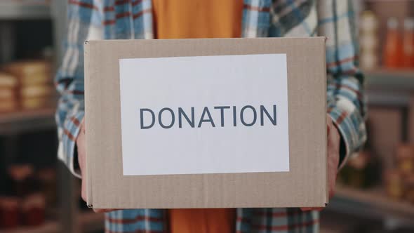 Close Up of Male Hands Holding Donation Box Among Storage