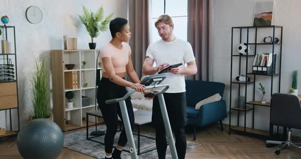 Couple Training Together on Treadmill Using Special Fitness Instruction on Tablet Device at Home