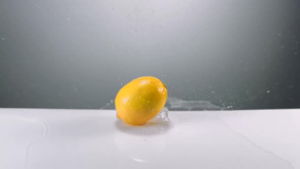 Slo-motion whole lemons falling on water