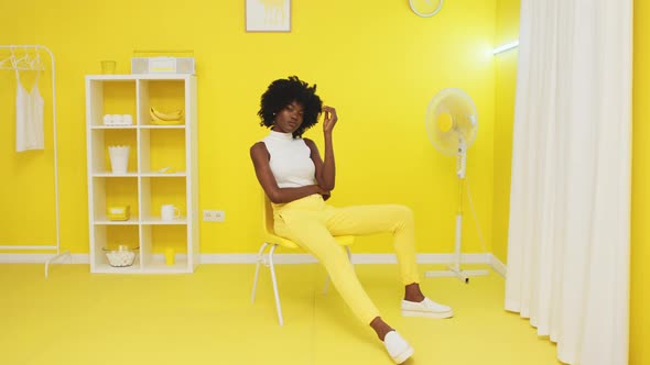African Woman Sitting In Yellow Office and Looking at Camera