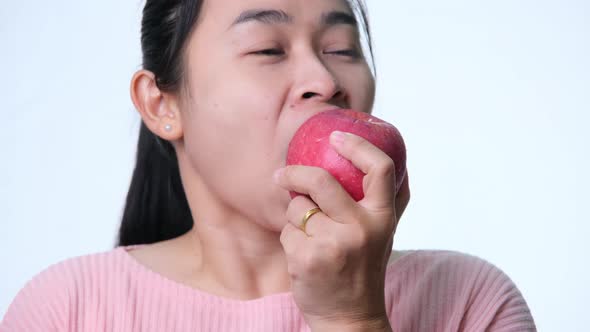 Asian woman holding an apple with a bite and smile showing strong teeth