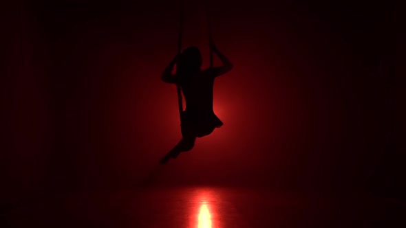 Silhouette Aerialist Girl Doing Acrobatic and Flexible Tricks on Red Aerial Silks Tissues on Red