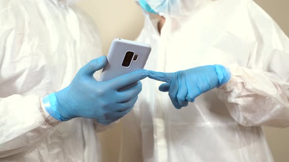 doctor in ppe calls a colleague to show information on mobile phone while they talk