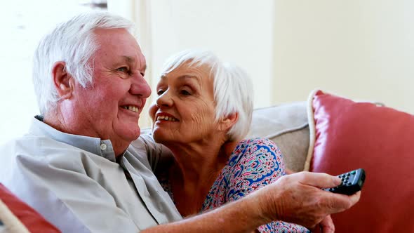 Senior couple talking while watching television in living room