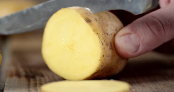 Male Hand with a Knife Cut Off a Piece of the Potatoes. 