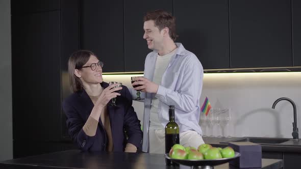 Positive Brunette Man Telling Celebratory Toast To Boyfriend in the Kitchen. Camera Approaches To