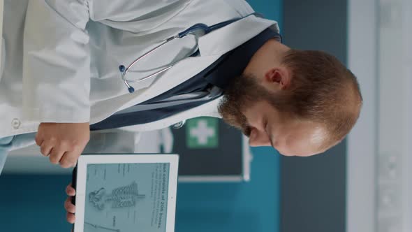 Vertical Video Male Doctor Showing Human Skeleton Illustration on Digital Tablet