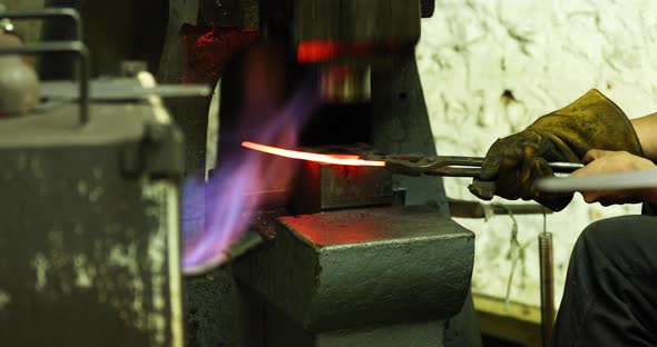 Bladesmith working with hot blade at hydraulic forge hammer