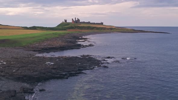 Iconic english Dunstanburgh Castle at sunset, Northumberland, England, UK. Aerial drone view