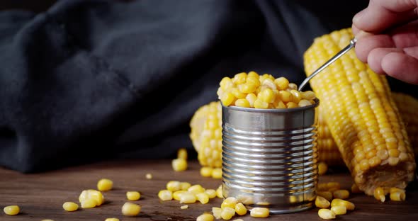Man's Hand Takes the Spoon Canned Corn From Cans. 