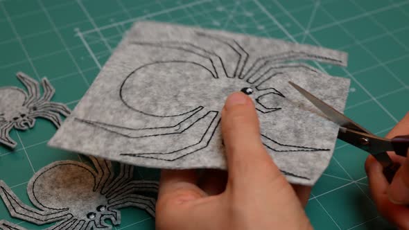 Woman scissoring out the spider from grey felt. Preparation for the Celebration Halloween Day