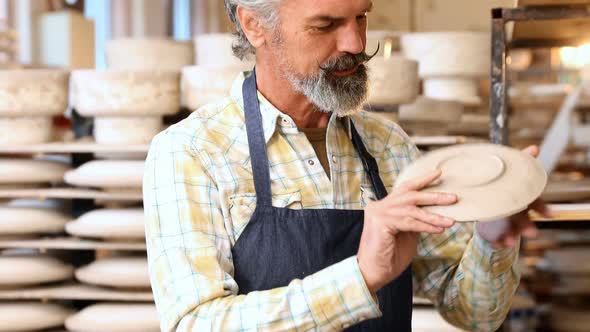 Male potter checking ceramic plate 4k