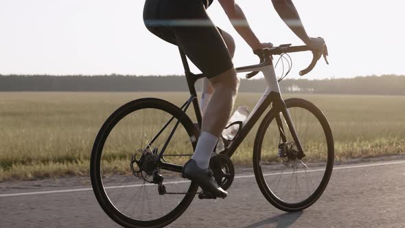 Closeup of Man Riding a Road Bike at the Sunset on a Highway Wearing Helmet