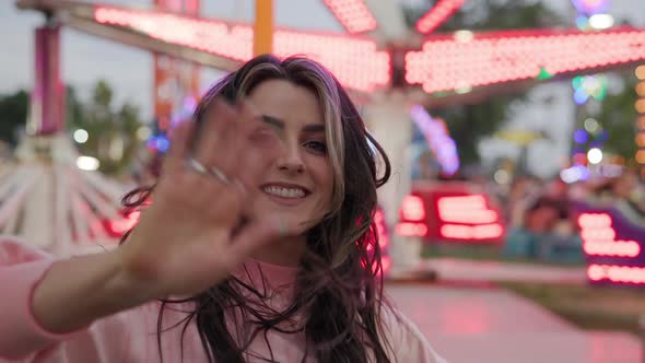 Young woman turning and waving as hair blows in wind