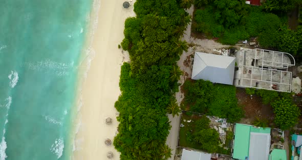 Wide overhead tourism shot of a white sand paradise beach and aqua turquoise water background in col