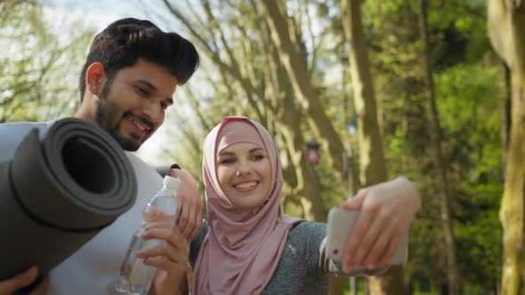 Cheerful Muslim Man and Woman in Hijab Taking Self Portrait on Smartphone While