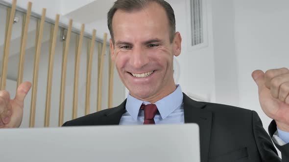 Middle Aged Businessman Celebrating Success, Working on Laptop