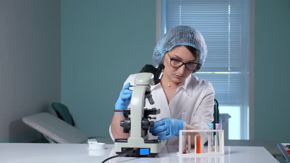 Lady Adjusts Microscope Working with Sample in Hospital