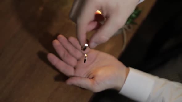 Groom in a White Shirt Drops Wedding Rings To the Palm of His Hand. Man Touches the Rings