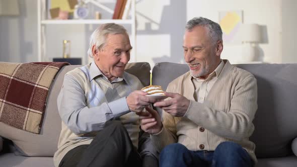 Aged Man Presenting Birthday Cake With Candle to Smiling Friend, Anniversary