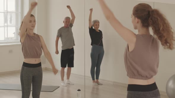 Fitness Instructor Showing Arm Stretching Exercises to Senior Couple