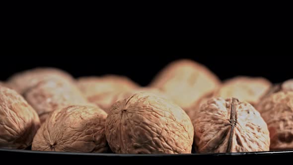 Lot of Walnuts in the Shell are Spinning on a Black Background