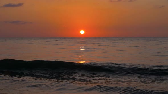 Sunset Over the Sea. The Sun and the Orange Sky Are Reflected in the Surf. Slow Motion Shot