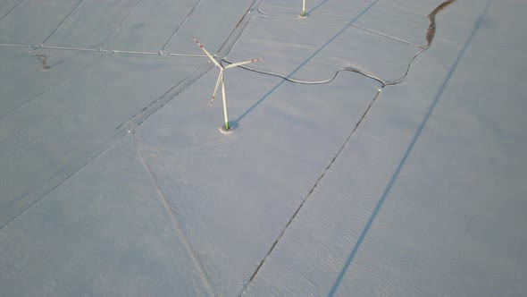 Aerial View Of Wind Turbines On Snow-Covered Farm Fields Of Northern Poland In Europe - drone shot