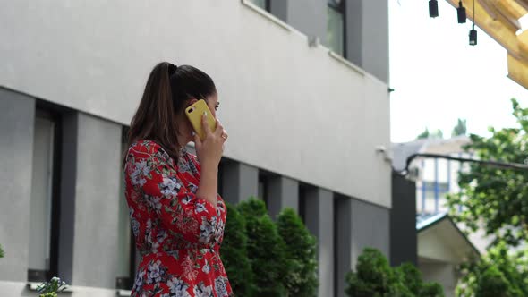 Beautiful girl in red dress, with flower pattern on the terace, outdoor in business centr.