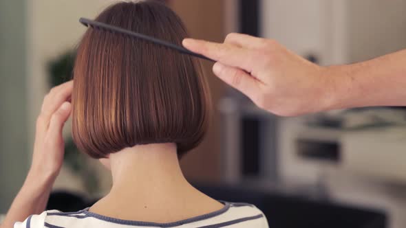 Hairdresser-stylist is cutting hair of a girl client