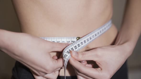 Waist Measurement. A Woman Measures Her Waist with a Centimeter Tape.