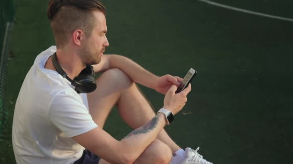 Basketball Player Having Rest Browsing Information in Cellphone
