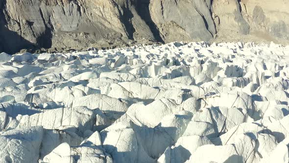 aerial drone flying over the deep crevasses in the cold and white Passu Glacier located in Hunza Pak