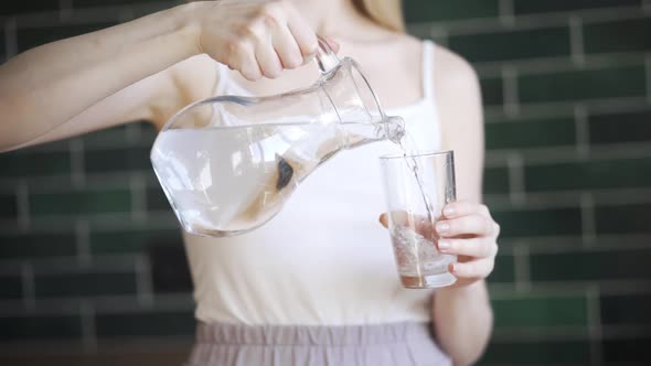 Young Pretty Woman Drinks Water in the Kitchen