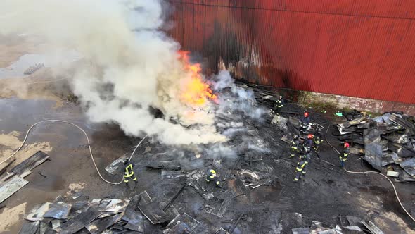 Aerial view of firemen fighting with fire near old factory biulding in industrial area.