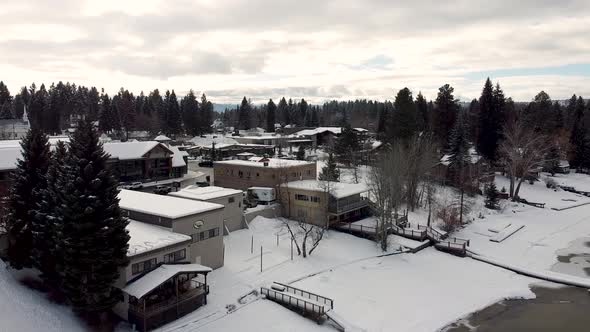 Snowy American small town in winter with slowing cars, houses, shops and surrounding trees in McCall