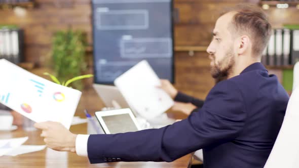 Successful Young Businessman Looking at Charts on His Tablet in the Conference Room