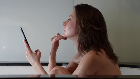 Lonely Woman is Taking Bath at Evening Using Smartphone for Communicating Sending Messages