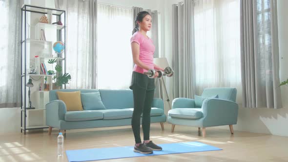 Young Asian Woman With Dumbbells Exercising At Home