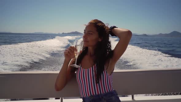 Brunette Female Drinks Champagne While Saling on the Motor Boat at the Sea She Enjoys Her Vocation
