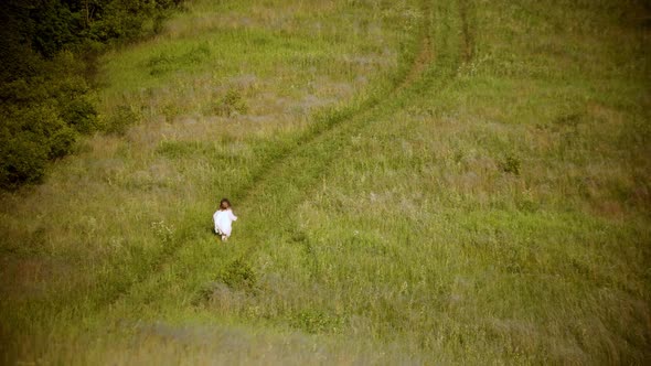 A Little Girl in White Clothes Running on the Green Field