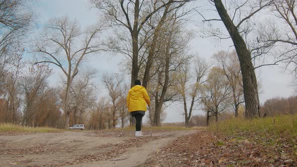 Senior Woman Making Nordic Walking in the Autumn Forest. Nordic Walking Race on Autumn Trail