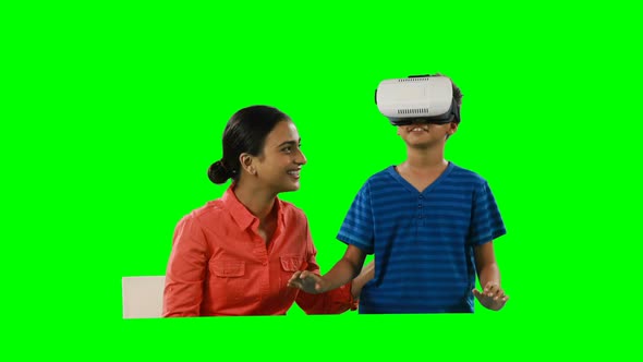 Smiling mother assisting son in using virtual reality headset 4k